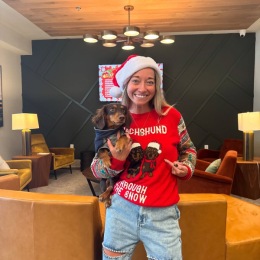 a woman holding her dog and wearing a Christmas sweater